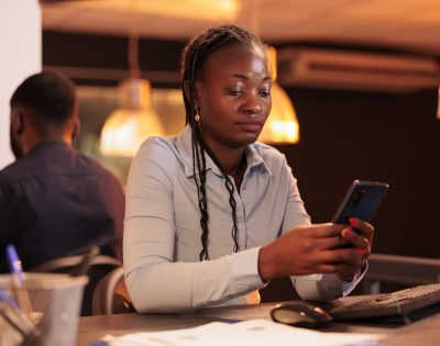 office worker looking smartphone app plan presentation using social media website create email report analyzing online data mobile phone paperwork research min scaled e1760197754311